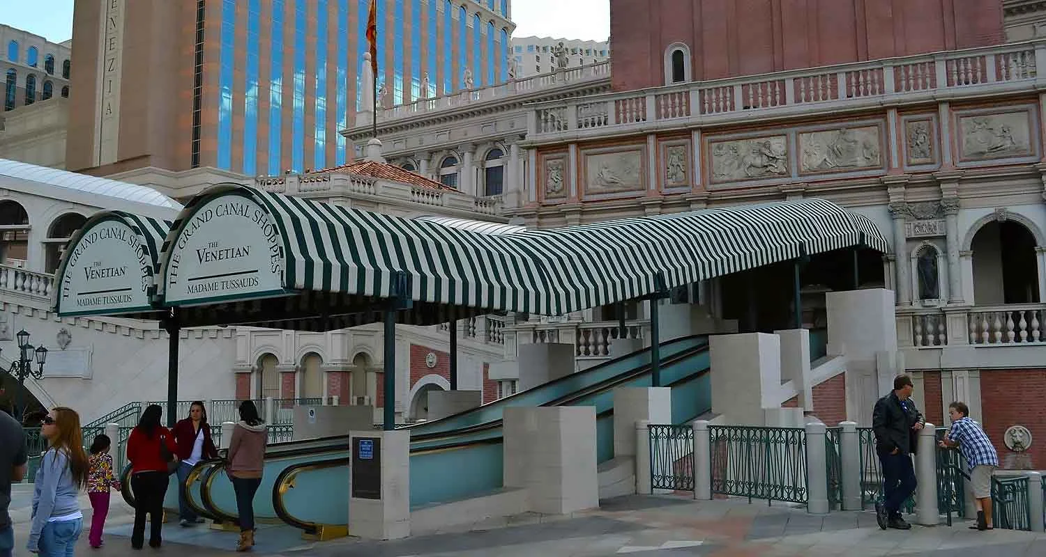 | Las Vegas Awning and StructuresStriped green and white awnings cover escalators leading to The Venetian in Las Vegas, providing sun protection and enhancing the architecture. People are seen approaching the entrance, highlighting effective Las Vegas awnings for desert climates.