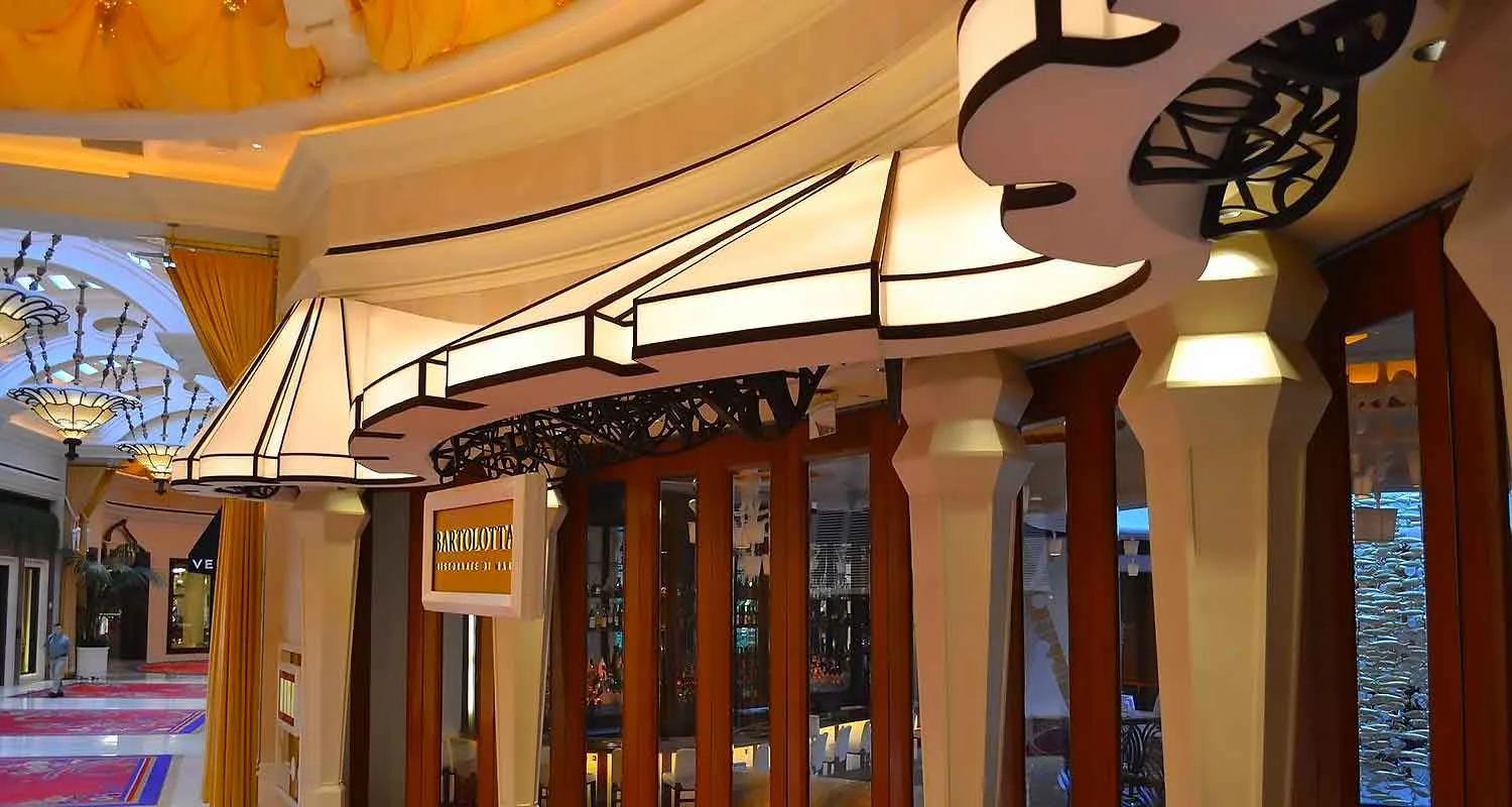 | Las Vegas Awning and StructuresElegant storefront featuring custom awnings with intricate designs, providing sun protection in a Las Vegas shopping area. The awnings complement the warm interior lighting and luxurious decor, showcasing professional awning installation expertise.