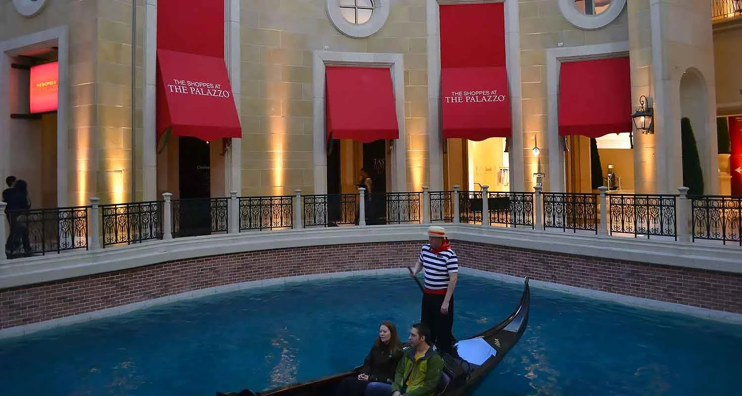 | Las Vegas Awning and StructuresA gondola glides on a canal beneath vibrant red storefront awnings at The Palazzo in Las Vegas, offering a picturesque view of custom awnings that provide shade and enhance the ambiance of this elegant shopping destination.