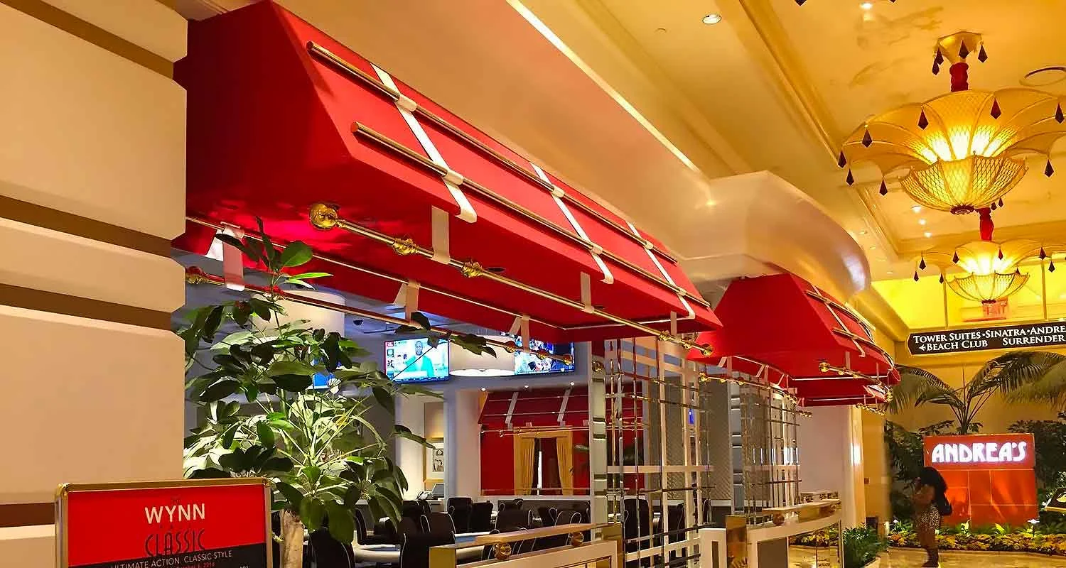 | Las Vegas Awning and StructuresRed commercial awnings adorn a luxurious indoor setting with elegant lighting and greenery, showcasing Las Vegas awnings for retail spaces.